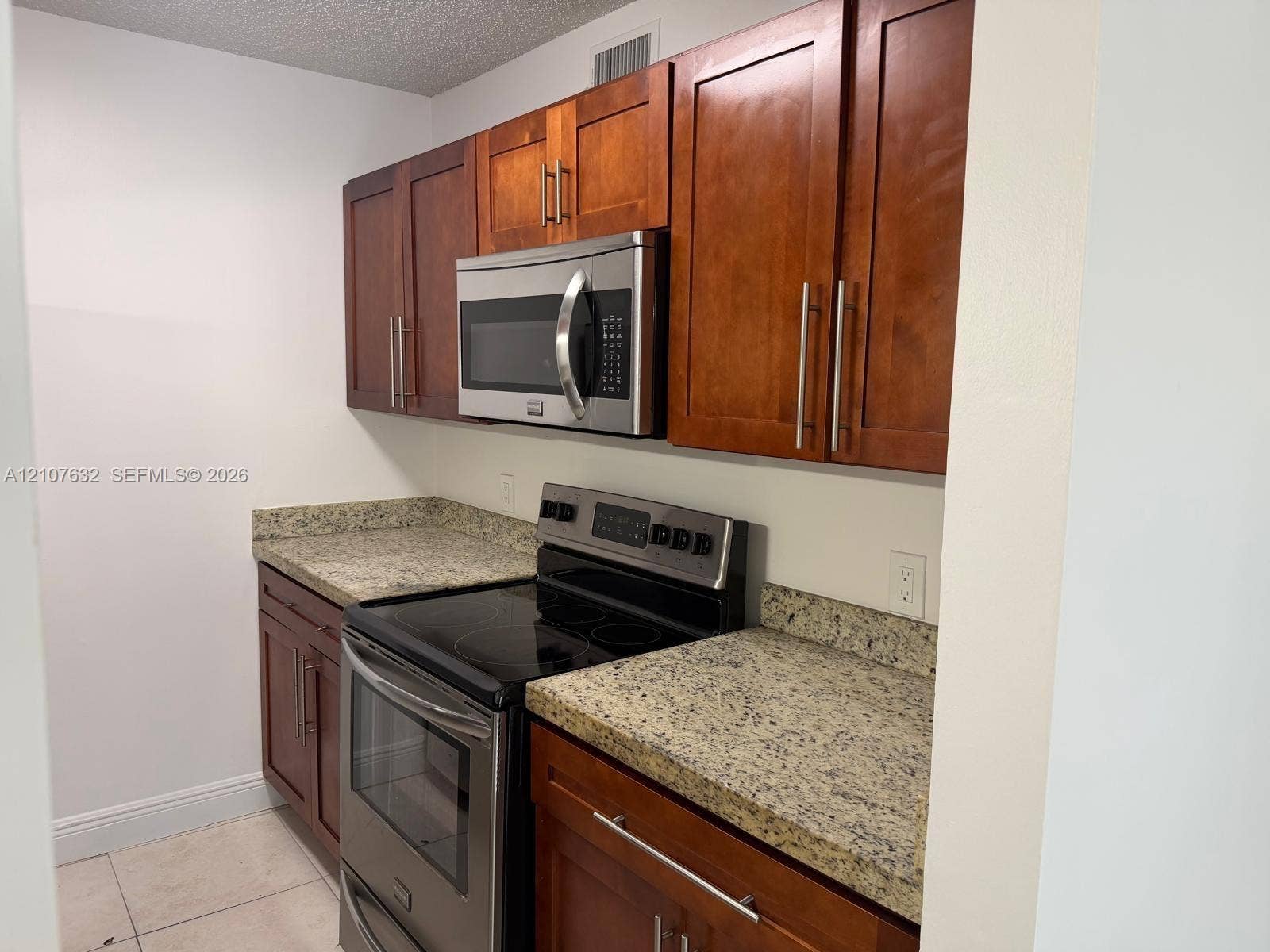 4501 W Mcnab Road, #13, Pompano Beach, Pompano Beach, FL 33069 Kitchen featuring shaker-style wood cabinetry, stone countertops, stainless steel appliances, and tile flooring