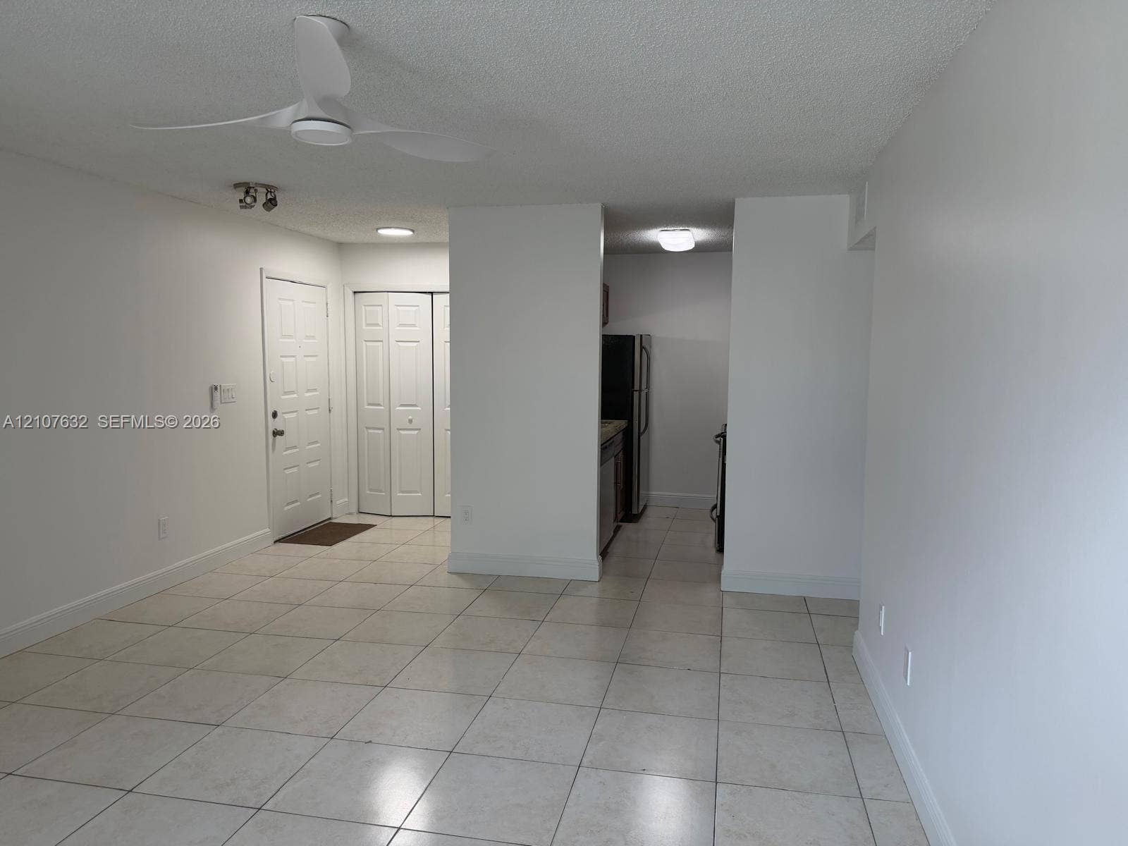 4501 W Mcnab Road, #13, Pompano Beach, Pompano Beach, FL 33069 Neutral-toned tile flooring, white interior walls, multi-blade ceiling fan, six-panel entry door, and bifold closet doors