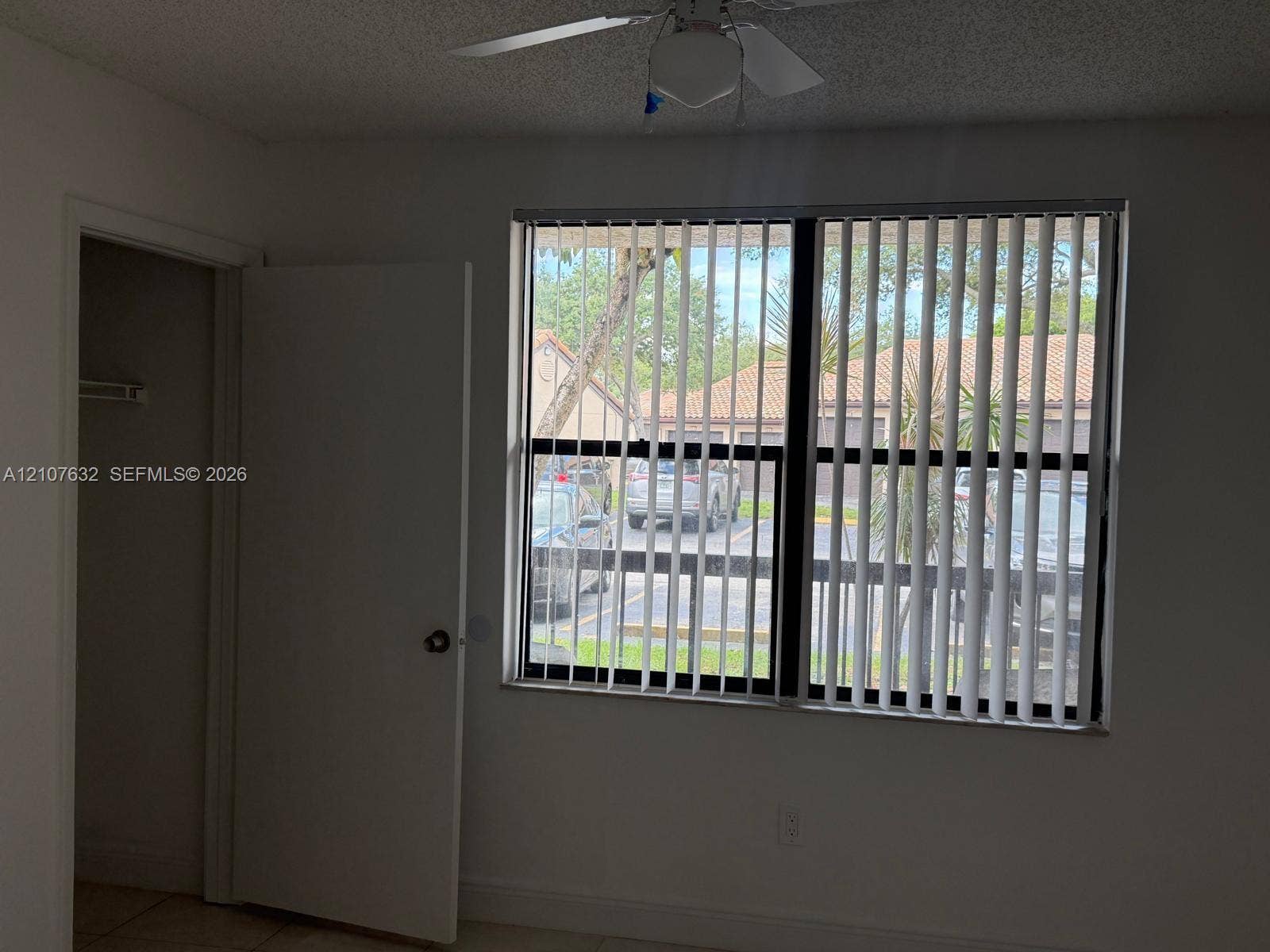 4501 W Mcnab Road, #13, Pompano Beach, Pompano Beach, FL 33069 Neutral-toned room featuring a ceiling fan with integrated light fixture, horizontal-sliding window with vertical blinds, and a built-in closet with interior shelving