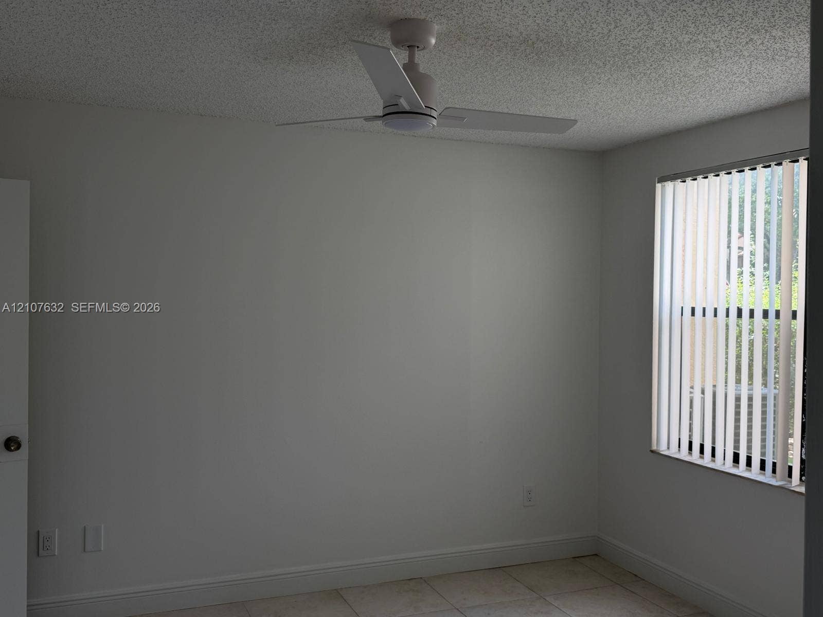 4501 W Mcnab Road, #13, Pompano Beach, Pompano Beach, FL 33069 Room interior featuring tile flooring, white vertical window blinds, and a white ceiling fan with integrated lighting