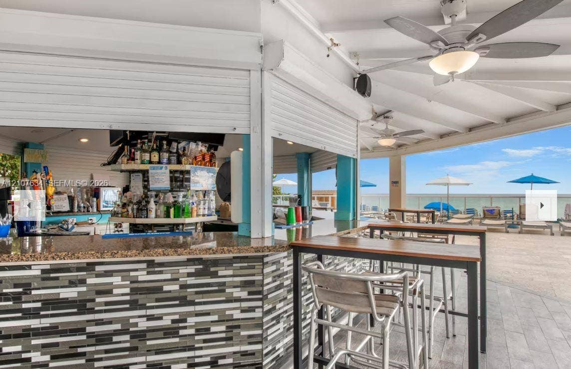 19201 Collins Avenue, #941, Sunny Isles Beach, FL 33160 Outdoor bar featuring a stone-tile facade, solid surface countertop, overhead ceiling fans, and integrated security shutters