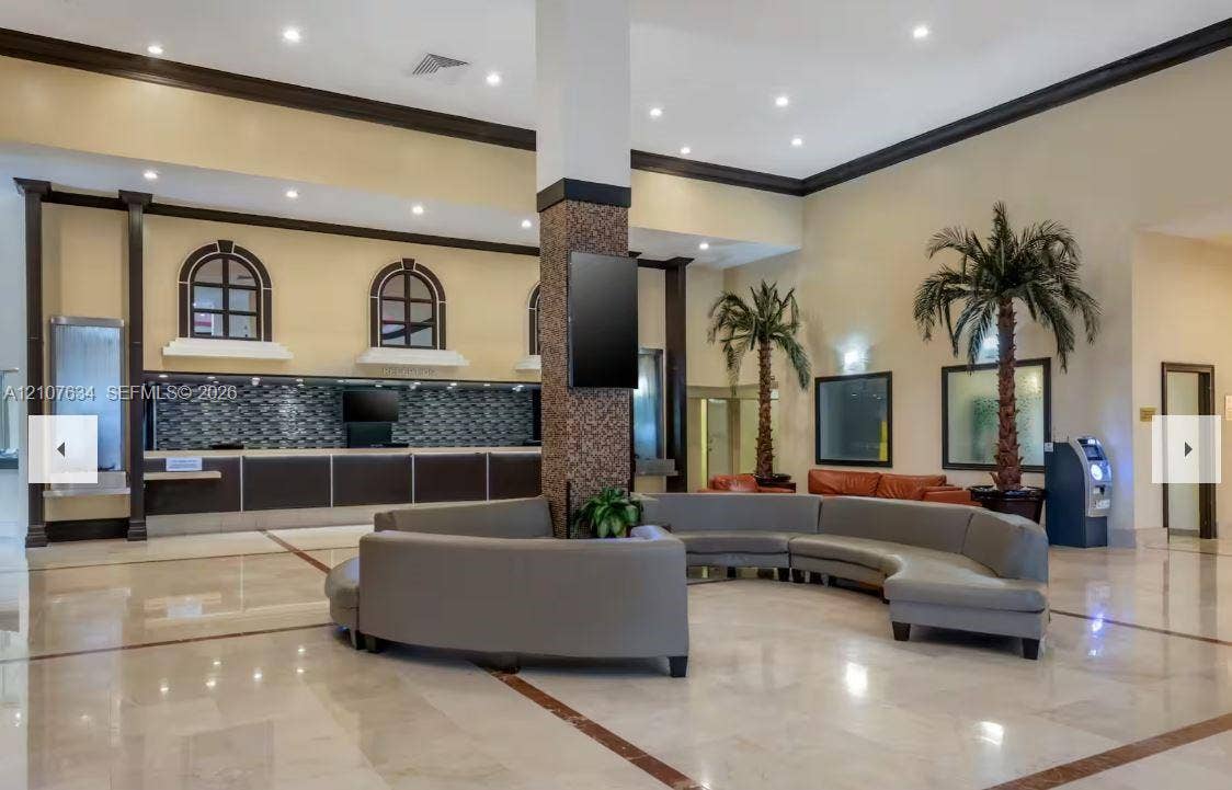 19201 Collins Avenue, #941, Sunny Isles Beach, FL 33160 Grand lobby featuring stone-tile flooring, vaulted ceilings with recessed lighting, custom built-in service counter with decorative tile backsplash, and architectural crown molding