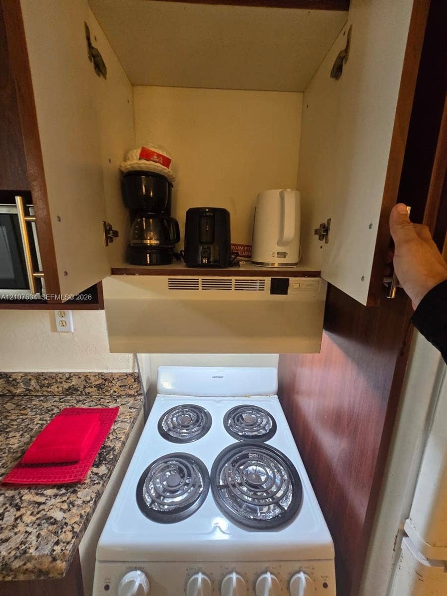 19201 Collins Avenue, #941, Sunny Isles Beach, FL 33160 White four-burner electric range with integrated hood ventilation and natural stone-finish countertops