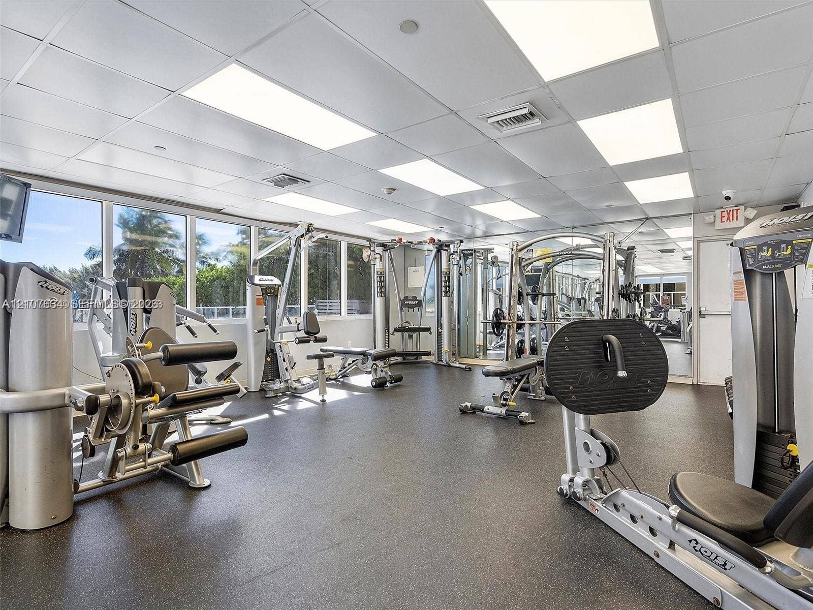 19201 Collins Avenue, #941, Sunny Isles Beach, FL 33160 Fitness center featuring floor-to-ceiling windows, rubberized flooring, mirrored walls, and grid ceiling panels with recessed lighting