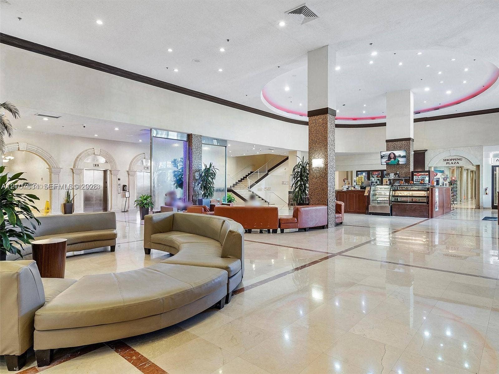 19201 Collins Avenue, #941, Sunny Isles Beach, FL 33160 Expansive lobby featuring polished stone flooring with decorative inlays, recessed ceiling lighting, textured stone-finish columns, and arched architectural entryways