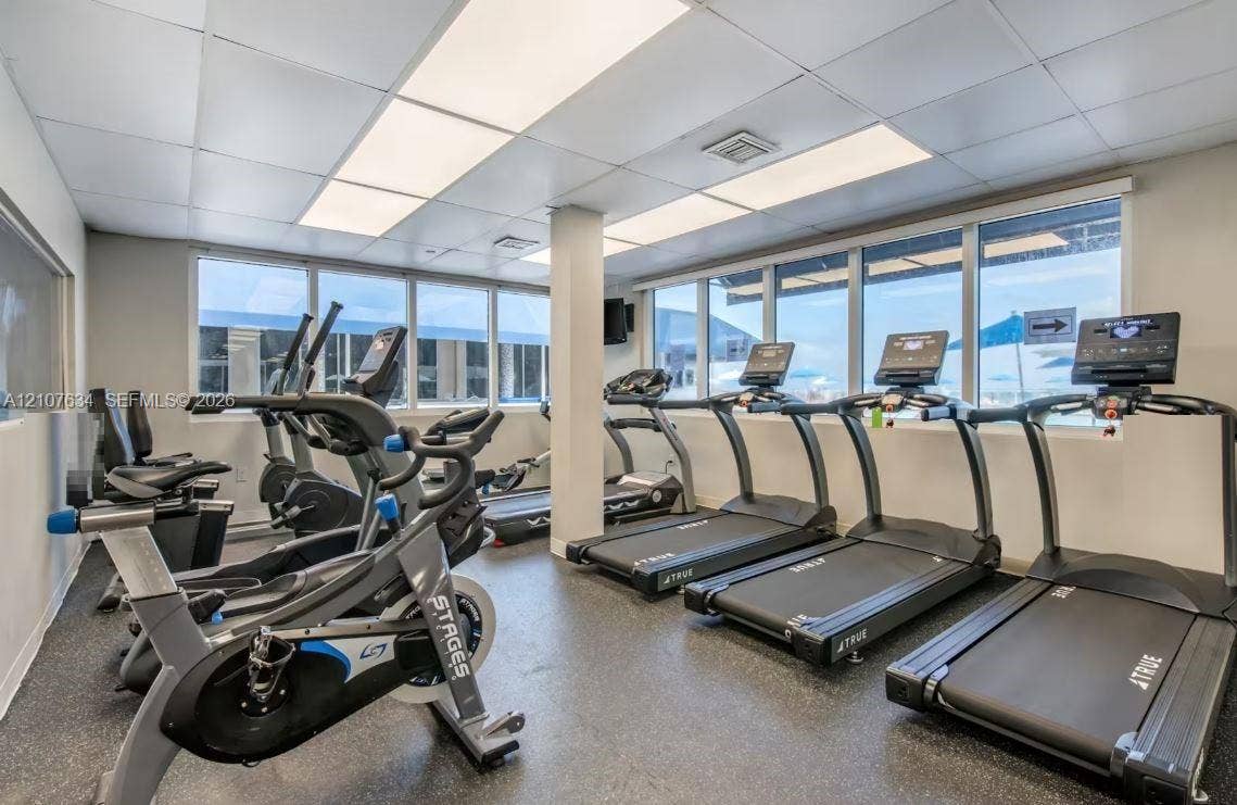 19201 Collins Avenue, #941, Sunny Isles Beach, FL 33160 Fitness room featuring rubberized flooring, expansive windows, fluorescent drop ceiling lighting, and a support column