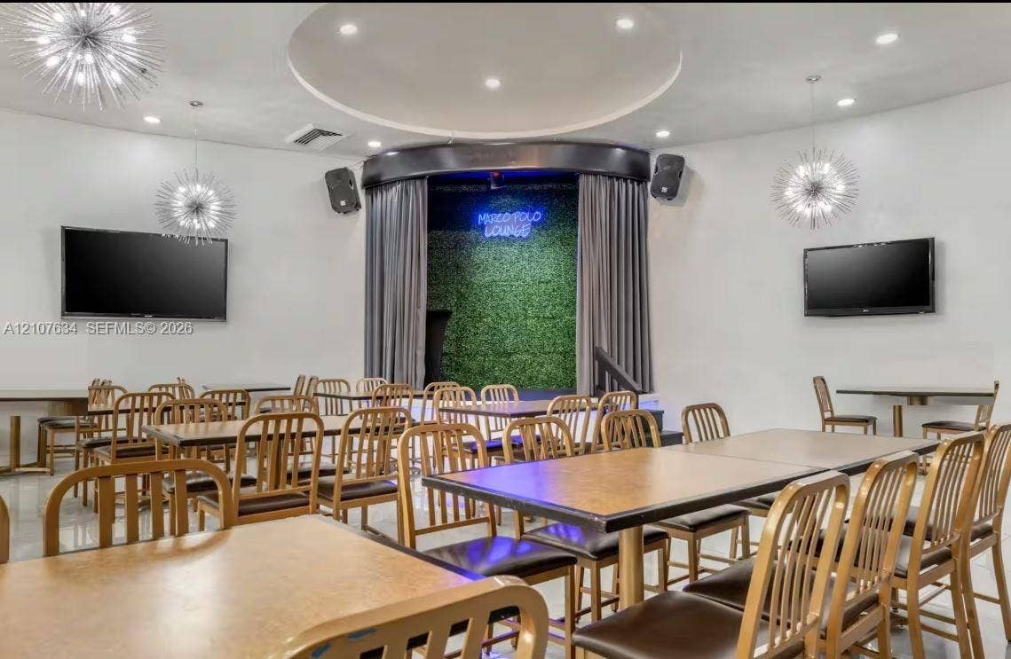19201 Collins Avenue, #941, Sunny Isles Beach, FL 33160 Entertainment space featuring a recessed stage with curtain backdrop, built-in sound system, decorative starburst pendant lighting, and a circular tray ceiling