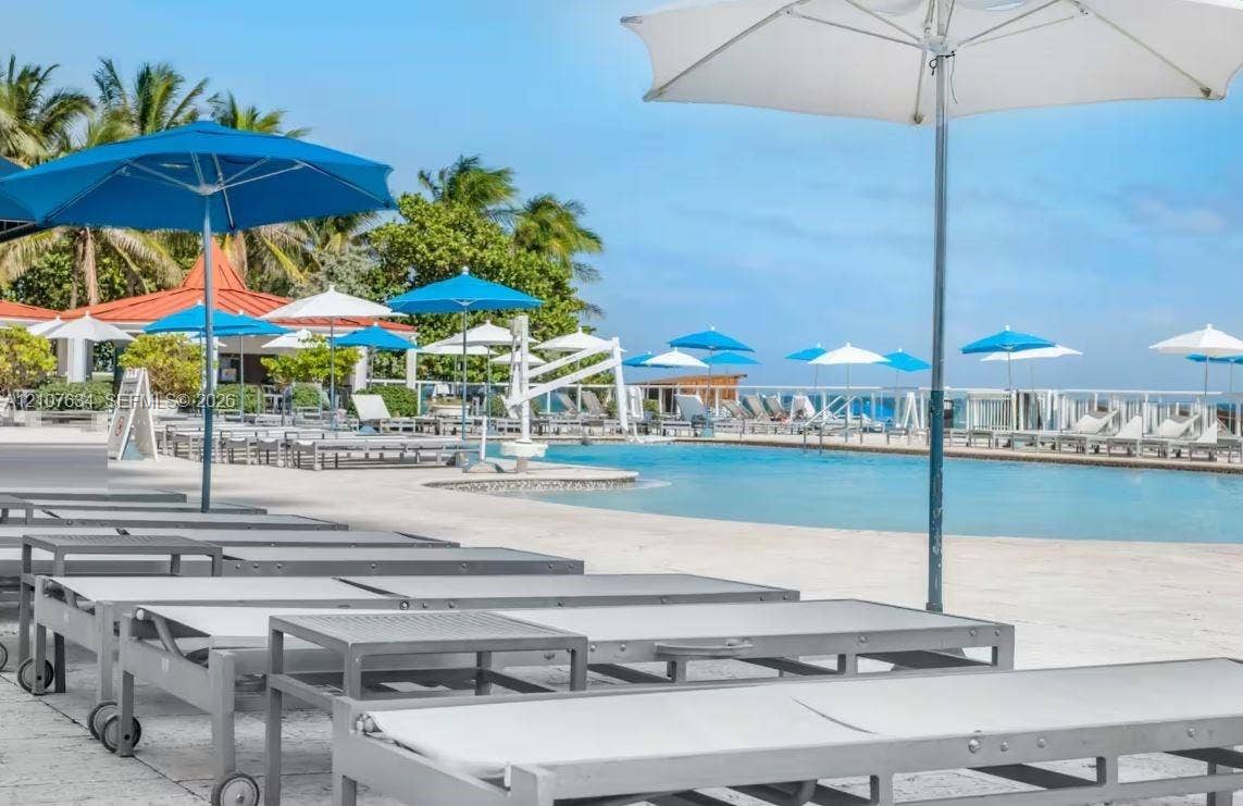 19201 Collins Avenue, #941, Sunny Isles Beach, FL 33160 Swimming pool with concrete pool deck, perimeter metal railing, and tropical landscaping