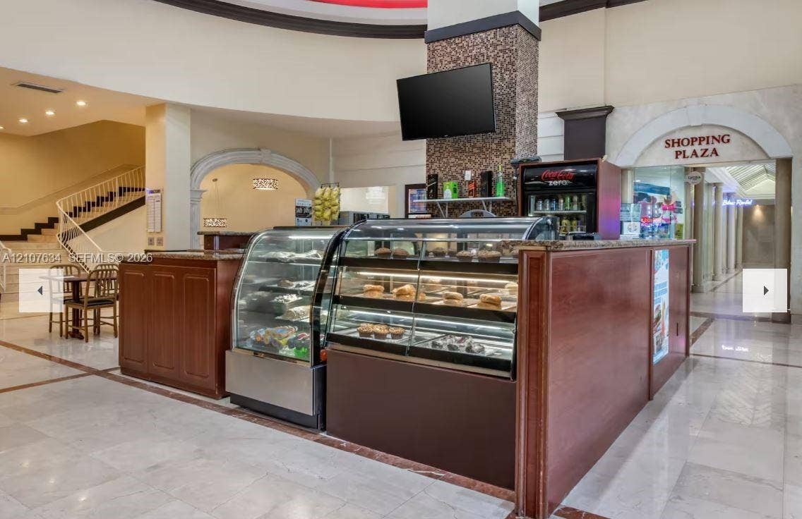 19201 Collins Avenue, #941, Sunny Isles Beach, FL 33160 Commercial service counter featuring wood-finish cabinetry, stone-style countertop, glass display cases, and an arched entryway architectural detail