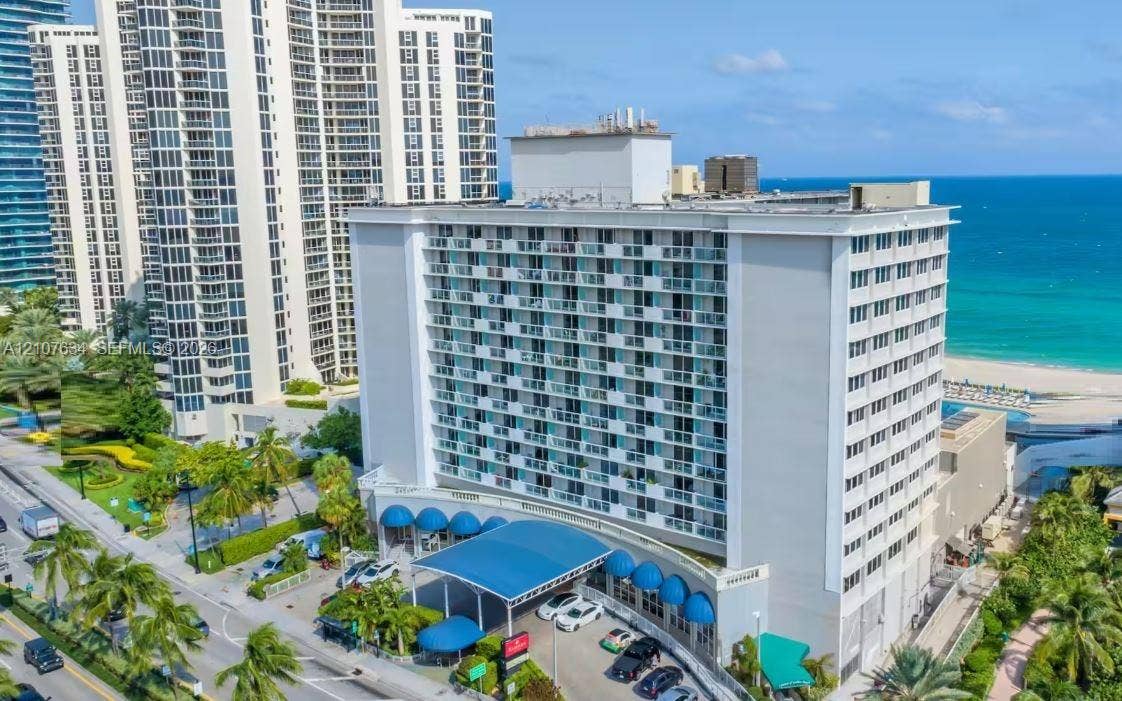 19201 Collins Avenue, #941, Sunny Isles Beach, FL 33160 High-rise coastal building featuring a prominent covered porte-cochre, balcony-lined exterior facade, and direct proximity to the oceanfront