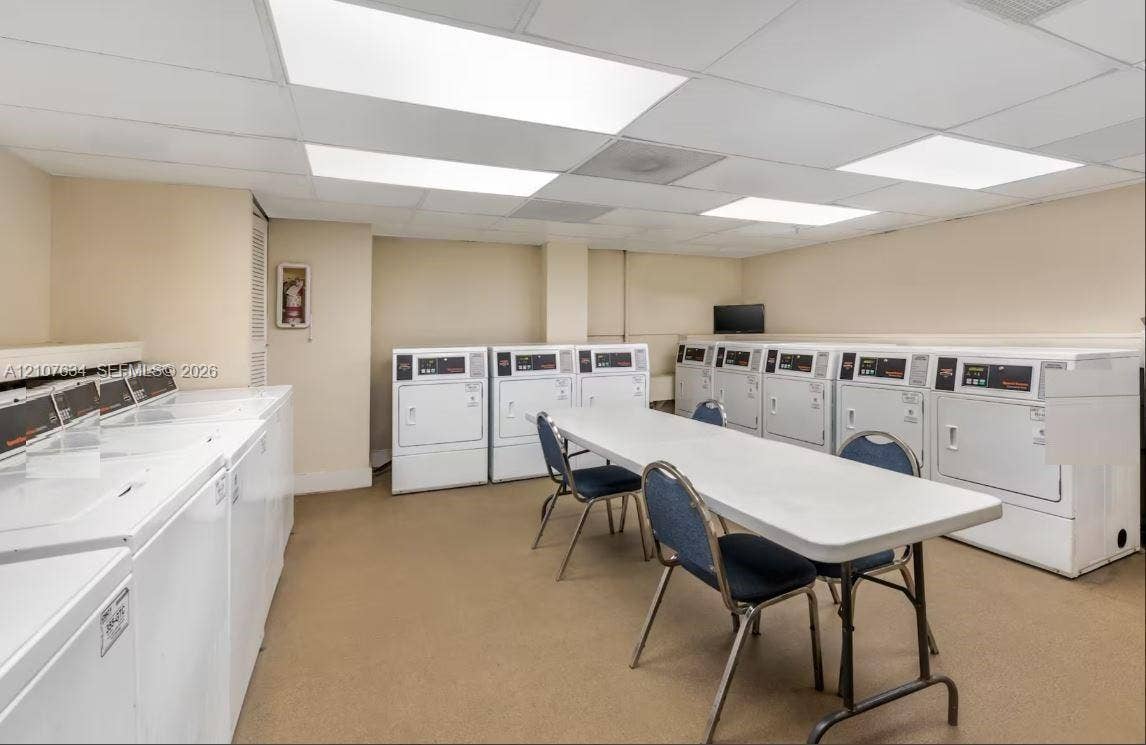 19201 Collins Avenue, #941, Sunny Isles Beach, FL 33160 Laundry facility featuring multiple white washing machines, commercial-grade clothes dryers, and recessed panel lighting