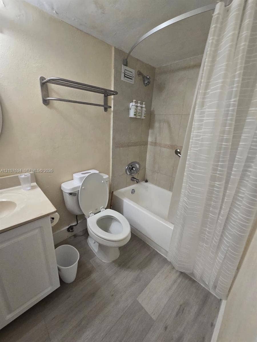 19201 Collins Avenue, #941, Sunny Isles Beach, FL 33160 Bathroom featuring wood-finish flooring, a white cabinet vanity, a shower-tub combination with tiled surround, and a metal wall-mounted towel rack