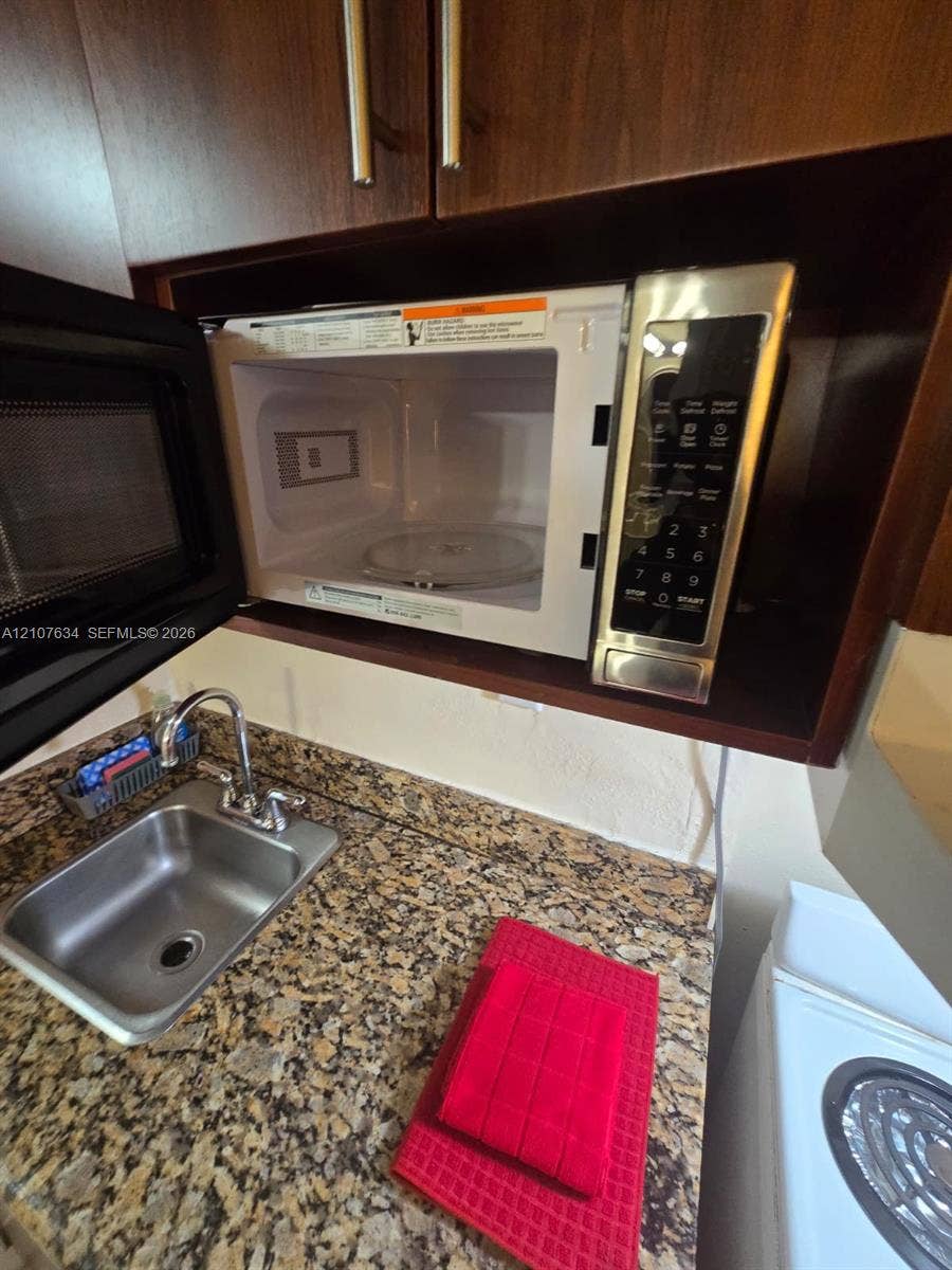 19201 Collins Avenue, #941, Sunny Isles Beach, FL 33160 Built-in microwave with stainless steel finish, stone-surface countertop, and stainless steel drop-in sink with gooseneck faucet