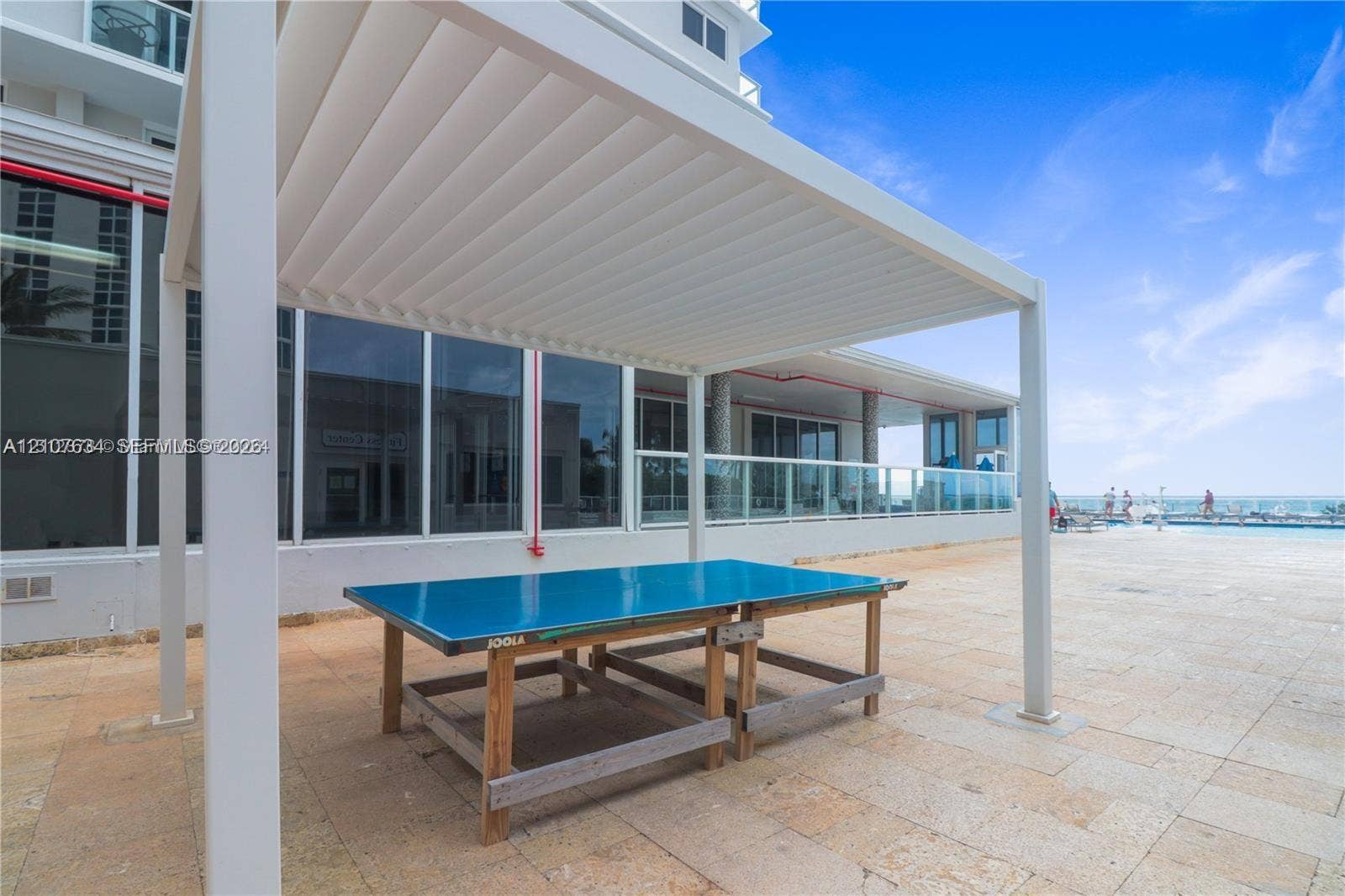 19201 Collins Avenue, #941, Sunny Isles Beach, FL 33160 Outdoor terrace featuring a louvered pergola, stone-tile flooring, and a glass-paneled railing