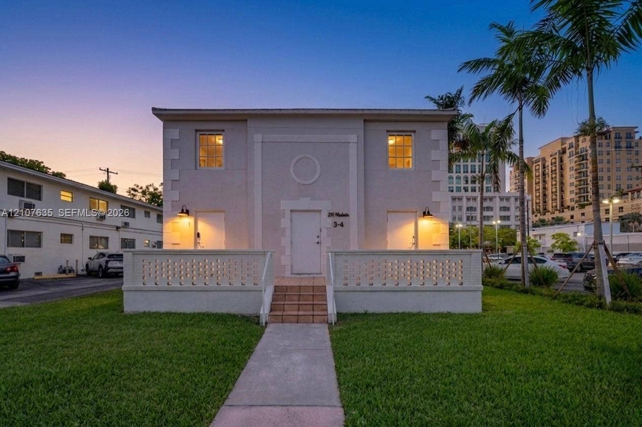 217 Madeira Avenue, #3, Coral Gables, Coral Gables, FL 33134 Two-story exterior featuring light-toned masonry, a decorative breeze block railing, exterior sconce lighting, and a central tiled stairway