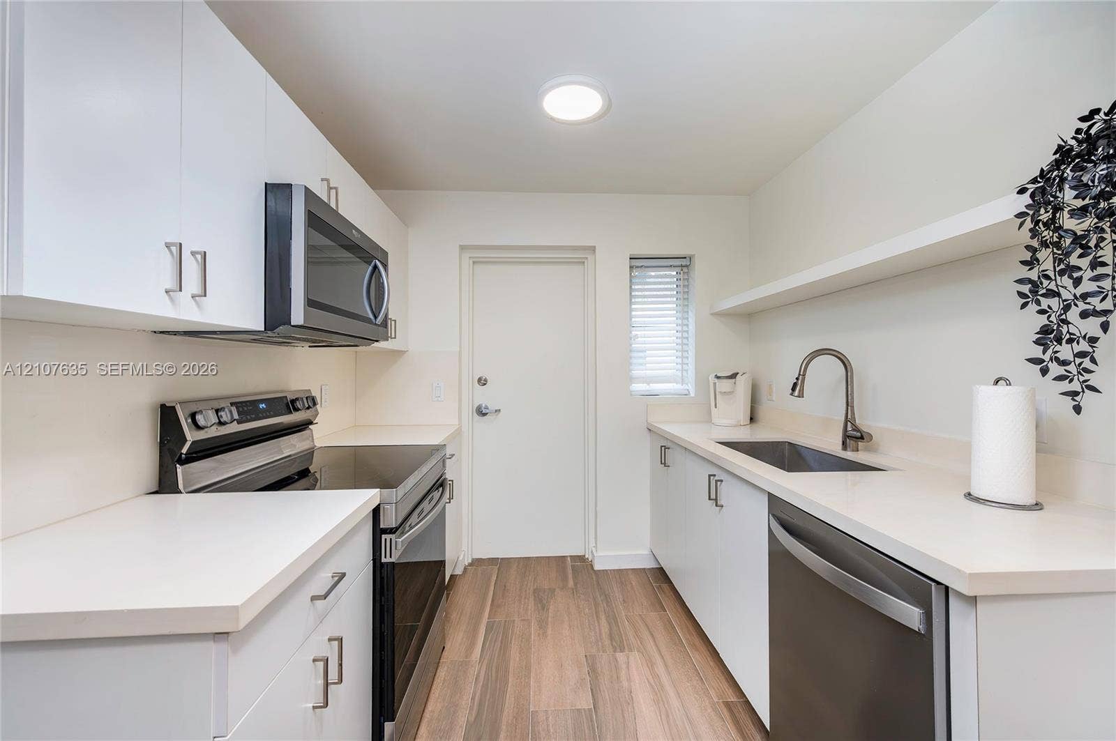 217 Madeira Avenue, #3, Coral Gables, Coral Gables, FL 33134 Kitchen featuring white flat-panel cabinetry, stainless steel appliances, solid-surface countertops, a single-basin undermount sink with a gooseneck faucet, and wood-finish flooring