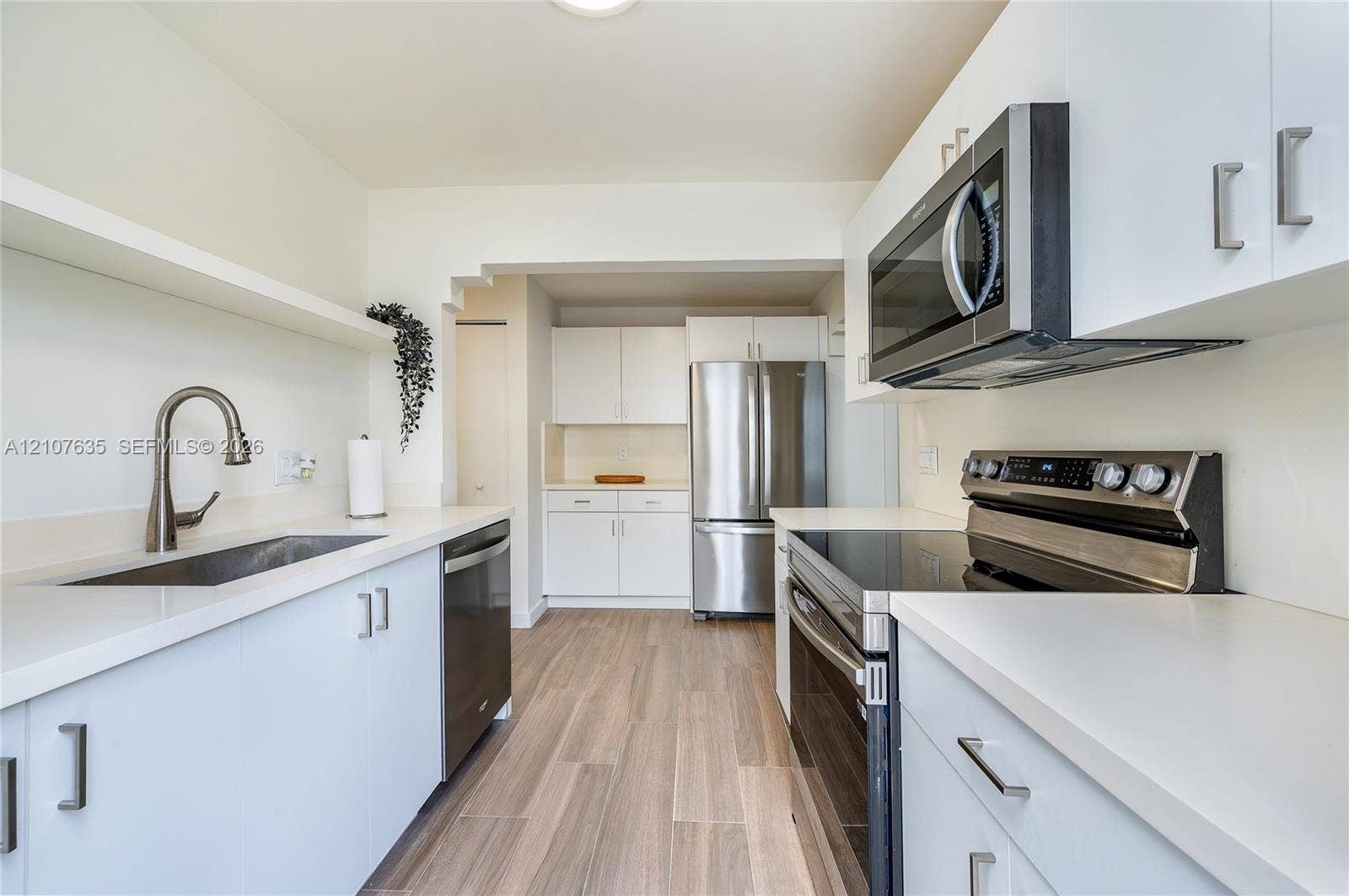 217 Madeira Avenue, #3, Coral Gables, Coral Gables, FL 33134 Kitchen featuring white flat-panel cabinetry, light-toned solid surface countertops, stainless steel appliances, a high-arc pull-down faucet, and wood-finish flooring