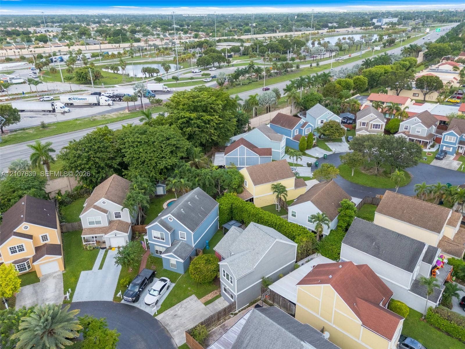 11735 SW 114th Terrace, #11735, Miami, Miami, FL 33186 Aerial perspective of a suburban neighborhood featuring multi-story residential structures, paved driveways, manicured green space, and dense mature tree coverage