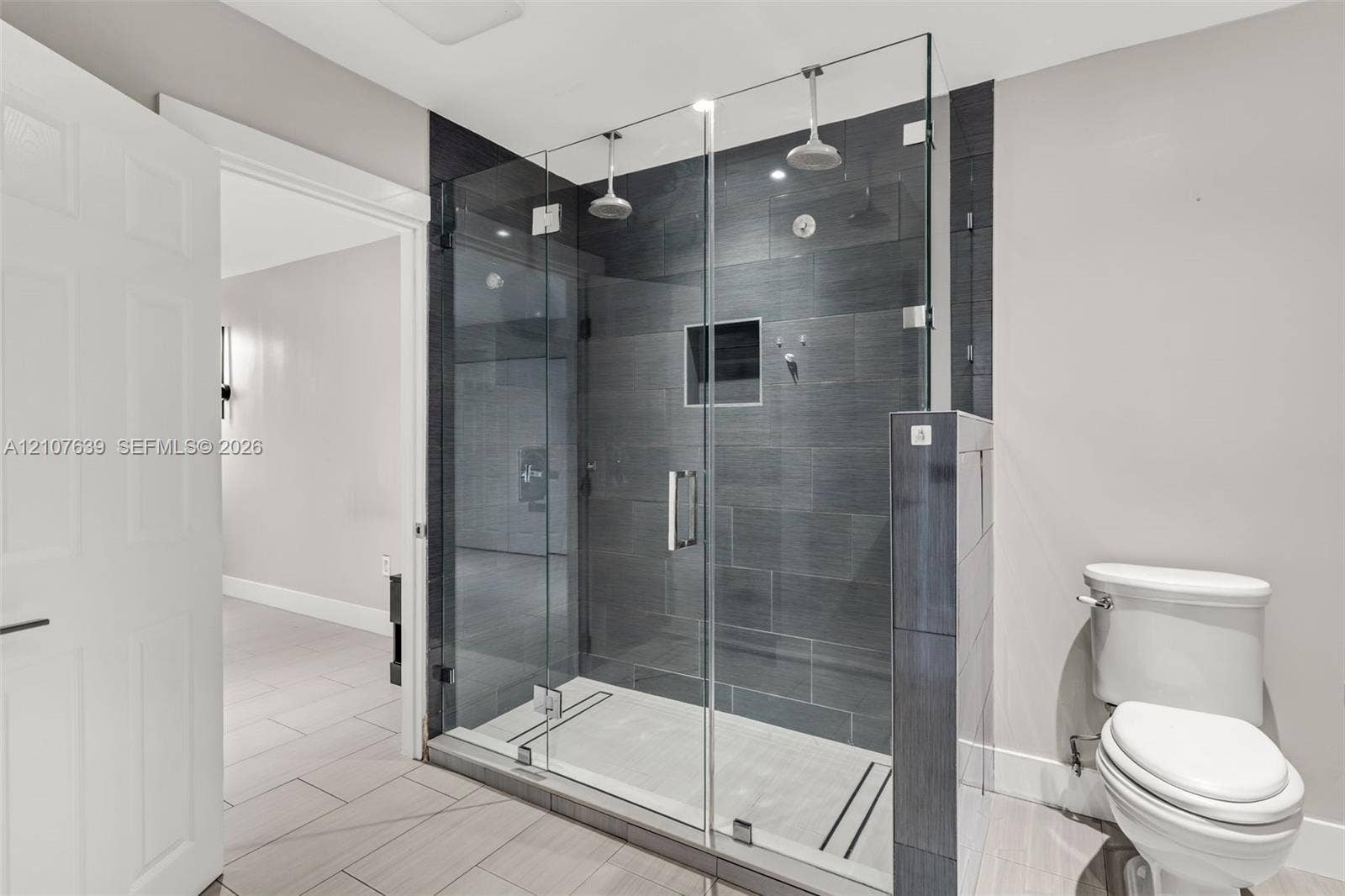 11735 SW 114th Terrace, #11735, Miami, Miami, FL 33186 Walk-in shower featuring a glass enclosure, dual overhead showerheads, recessed wall niche, and dark large-format tile surround