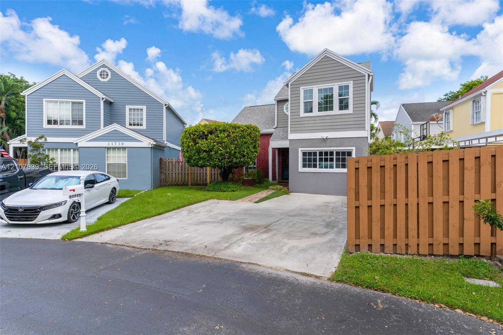 11735 SW 114th Terrace, #11735, Miami, Miami, FL 33186 Two-story exterior featuring grey horizontal siding, multi-pane windows, a concrete driveway, and a wood-slat privacy fence