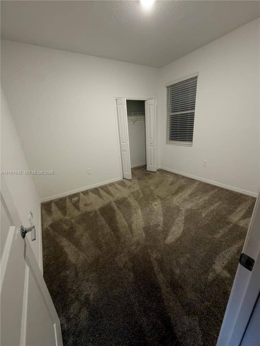 664 Tanaro Lane, Haines City, FL 33844 Neutral interior room featuring plush wall-to-wall carpeting, bi-fold closet doors, and a window with horizontal blinds
