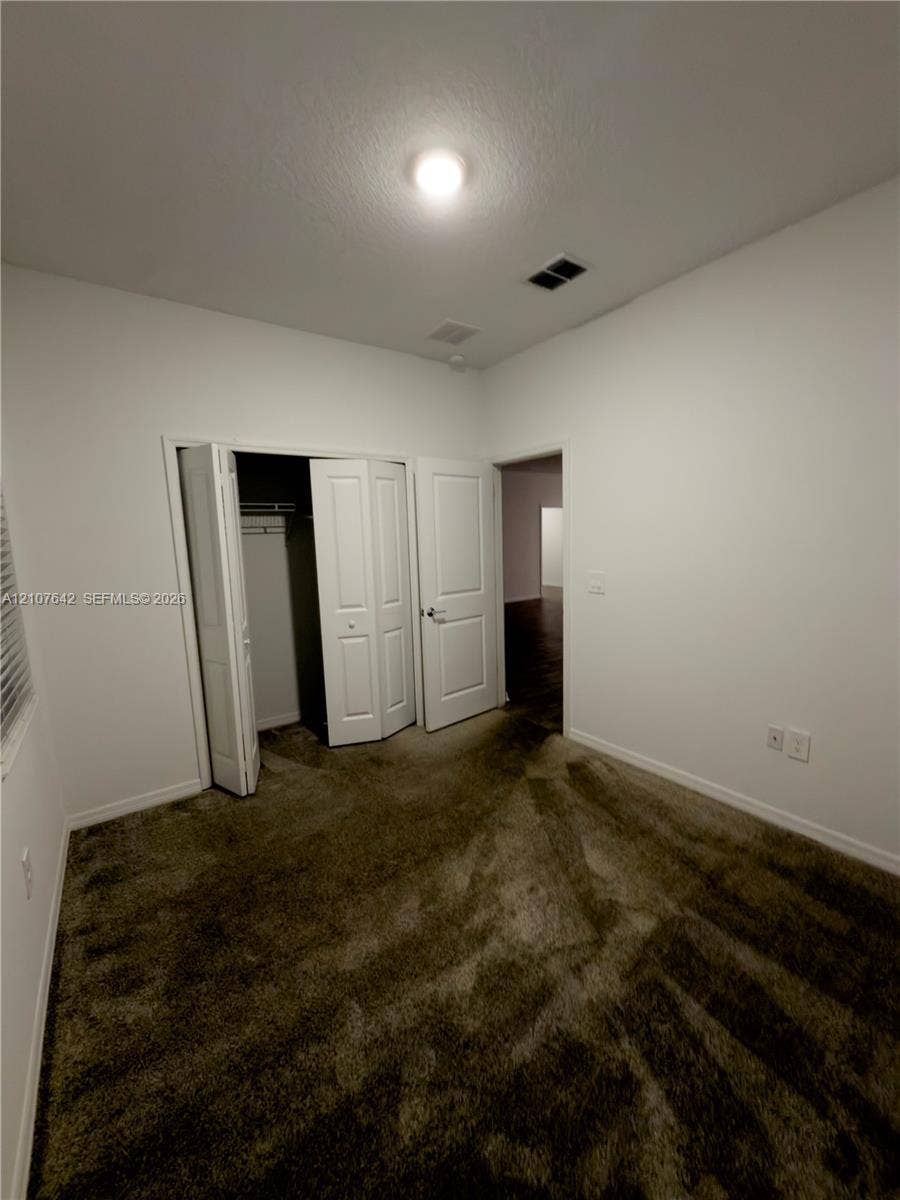 664 Tanaro Lane, Haines City, FL 33844 Room featuring neutral-toned carpeting, white walls, a multi-panel door, and a built-in closet with bi-fold doors