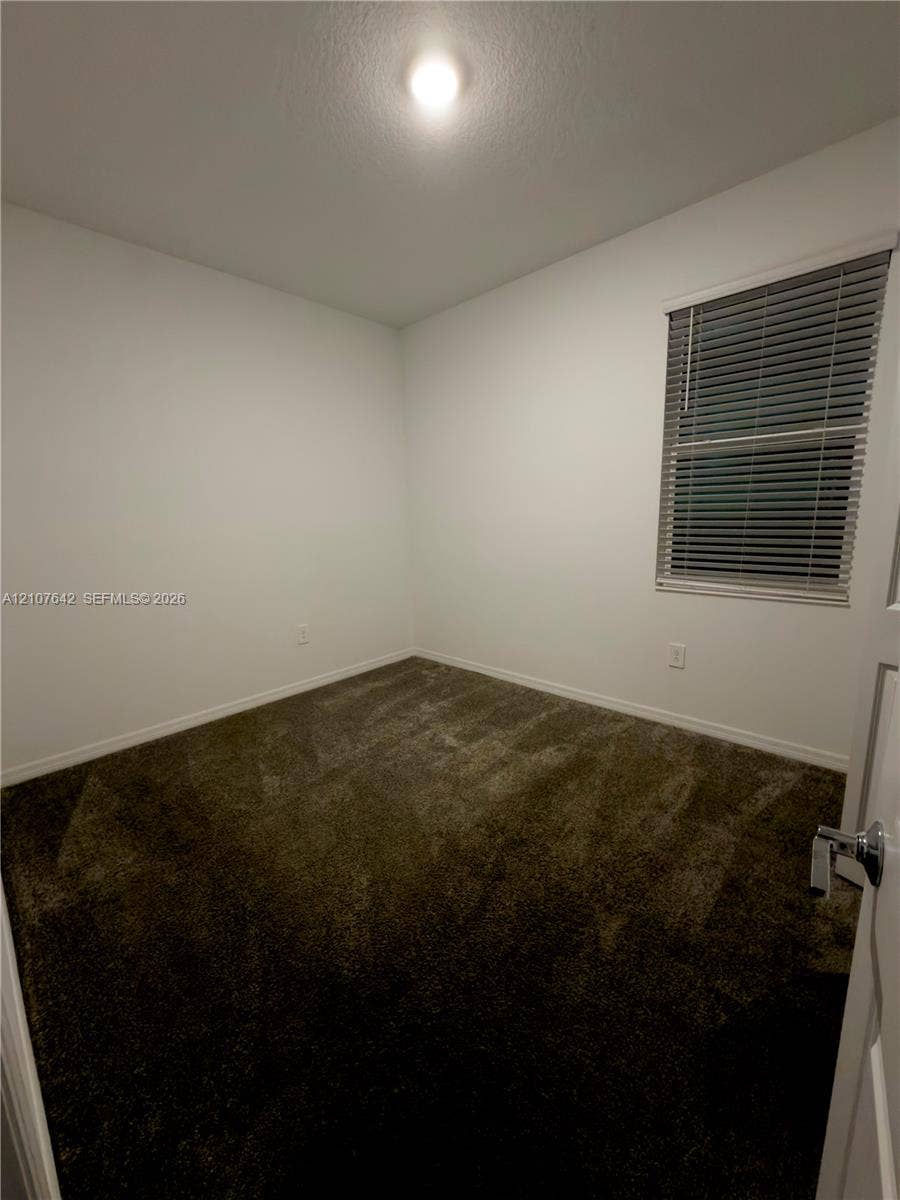 664 Tanaro Lane, Haines City, FL 33844 Neutral-toned wall paint, plush carpeting, ceiling-mounted light fixture, and horizontal window blinds