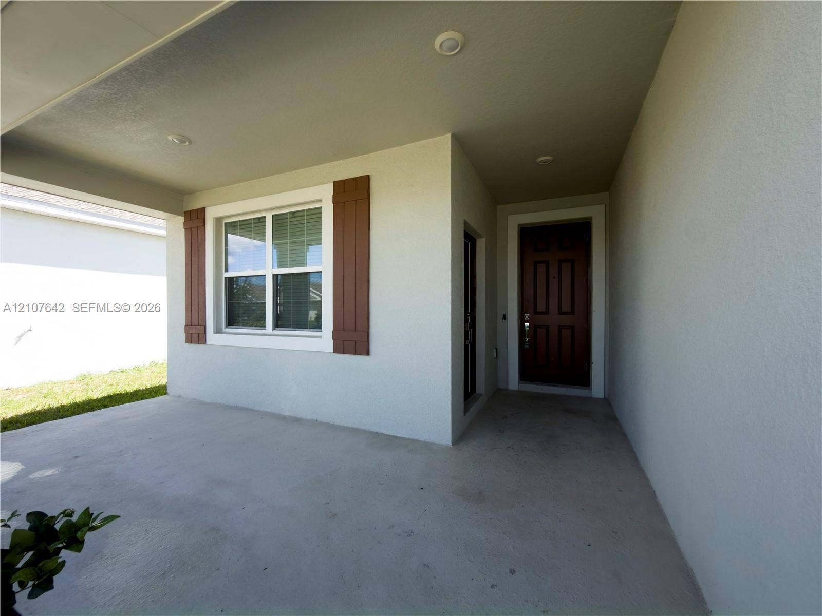 664 Tanaro Lane, Haines City, FL 33844 Covered entryway featuring a concrete floor, recessed lighting, a multi-panel door, and a single-hung window accented with decorative shutters