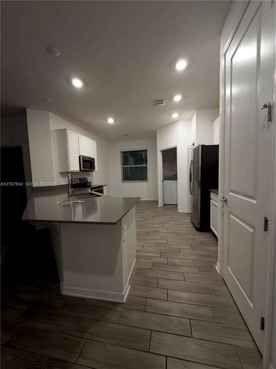 664 Tanaro Lane, Haines City, FL 33844 Kitchen featuring white cabinetry, solid-surface countertops, wood-finish flooring, recessed lighting, and stainless-steel appliances