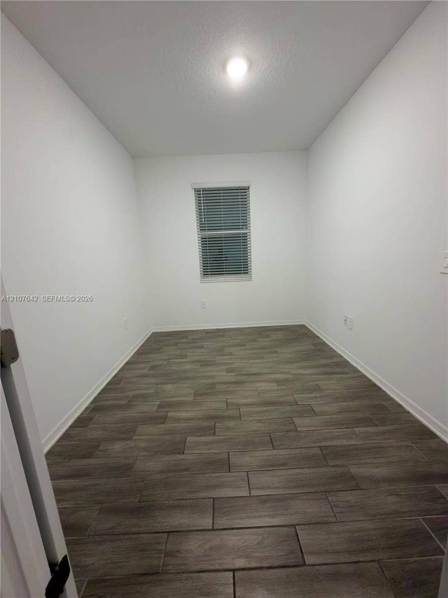 664 Tanaro Lane, Haines City, FL 33844 Room featuring wood-finish tile flooring, neutral wall tones, and a single window with horizontal blinds