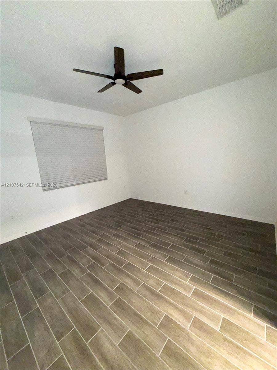 664 Tanaro Lane, Haines City, FL 33844 Room featuring wood-finish tile flooring, white walls, horizontal window blinds, and a multi-blade ceiling fan