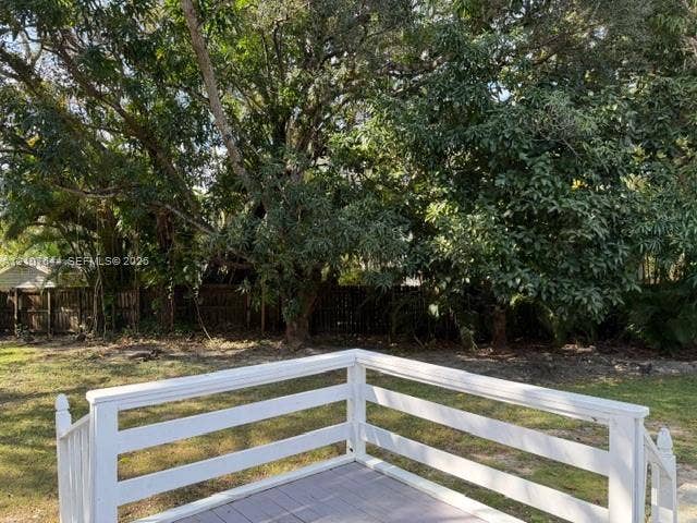 7550 SW 67th Avenue, South Miami, South Miami, FL 33143 Raised wood deck featuring white horizontal-rail fencing and stairs, situated in a backyard with mature trees and perimeter wood fencing