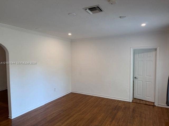 7550 SW 67th Avenue, South Miami, South Miami, FL 33143 Neutral-toned interior space featuring wood-finish flooring, recessed lighting, crown molding, a decorative arched entryway, and a six-panel door