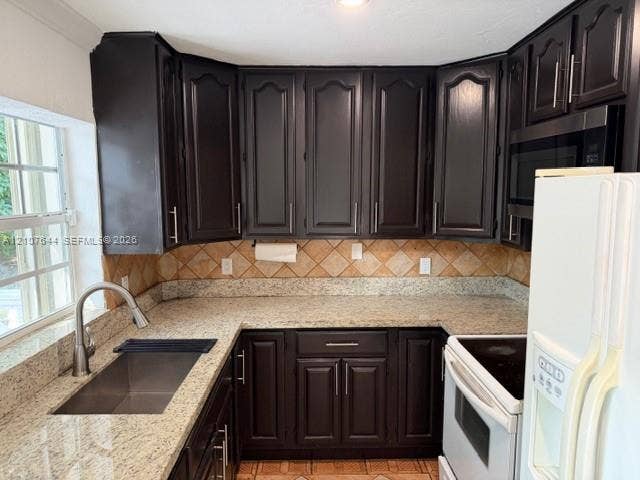 7550 SW 67th Avenue, South Miami, South Miami, FL 33143 Kitchen featuring dark-finish cabinetry with silver-tone hardware, speckled stone-surface countertops, square tile backsplash, and stainless steel under-mount sink with gooseneck faucet