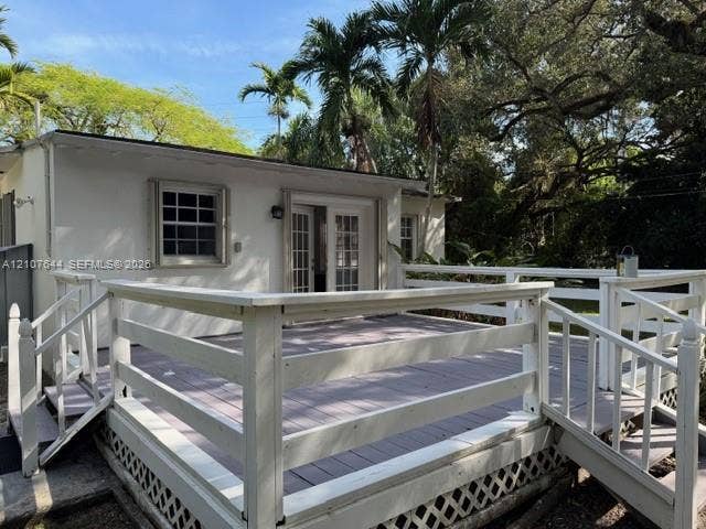 7550 SW 67th Avenue, South Miami, South Miami, FL 33143 Exterior deck featuring white railings, dual staircases, and lattice skirting, finished with multi-pane French doors