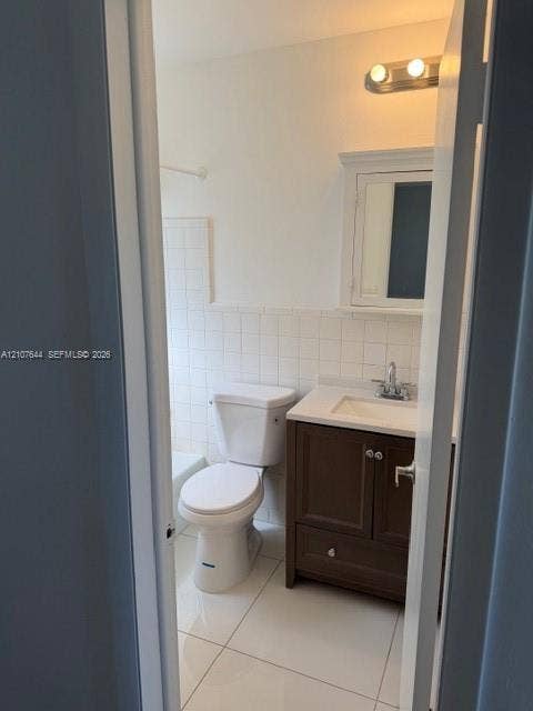 7550 SW 67th Avenue, South Miami, South Miami, FL 33143 Bathroom featuring a dark wood-finish vanity, light-toned countertop, inset medicine cabinet, tile flooring, and tile-surround tub