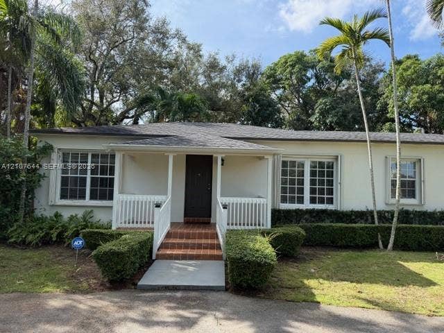 7550 SW 67th Avenue, South Miami, South Miami, FL 33143 Single-story exterior featuring a covered front porch, white railings, brick steps, and multi-pane windows