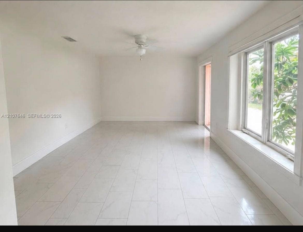 75 NW 116th Street, Miami, FL 33168 Spacious interior featuring large-format tile flooring, oversized windows, and a ceiling-mounted light fixture with fan