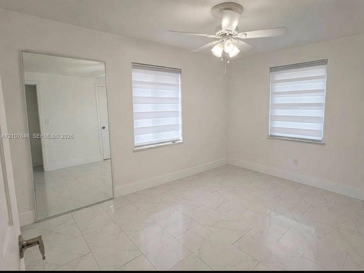 75 NW 116th Street, Miami, FL 33168 Large-format tile flooring, dual-pane windows with integrated adjustable shades, wall-mounted mirror panel, and ceiling-mounted light fixture with fan