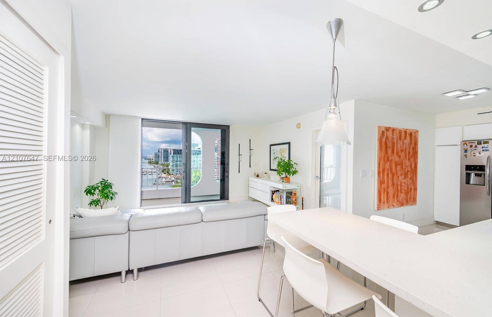 200 SE 15th Road, #PH-A, Miami, Miami, FL 33129 Open-concept area featuring light-toned tile flooring, recessed ceiling lighting, a neutral-toned kitchen island with stone-finish countertops, and floor-to-ceiling windows