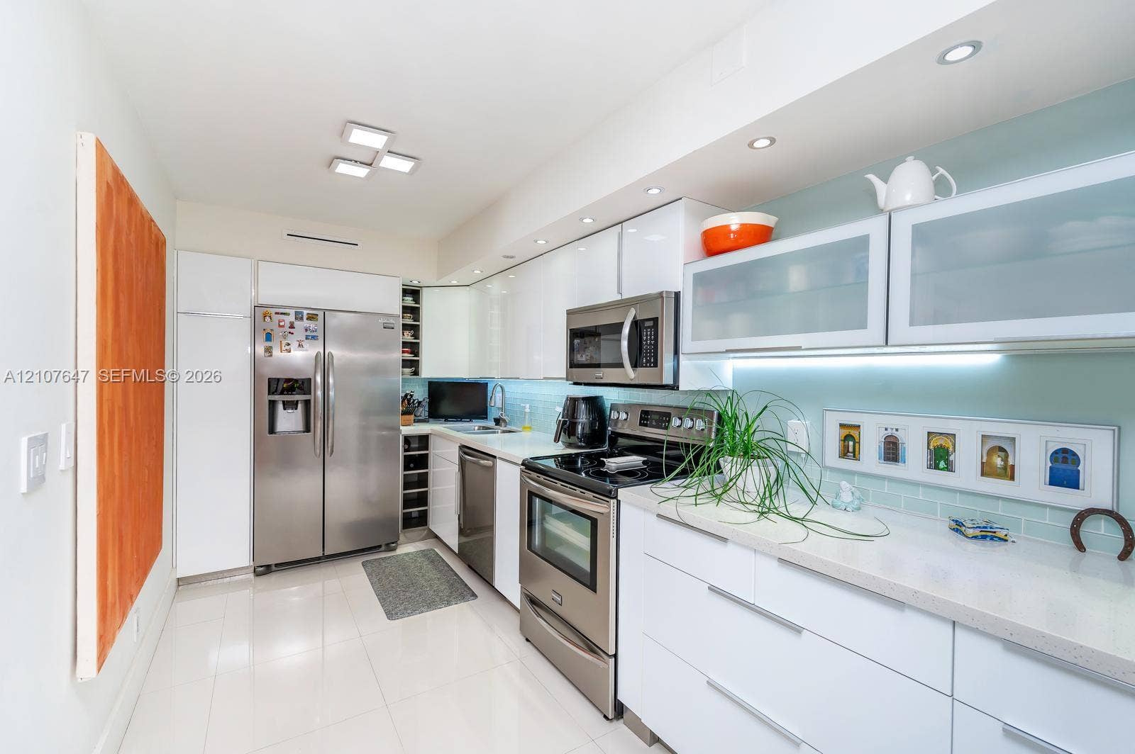 200 SE 15th Road, #PH-A, Miami, Miami, FL 33129 Kitchen featuring high-gloss white cabinetry, stainless steel appliances, light-toned stone countertops, glass-front upper cabinet doors, and recessed ceiling lighting