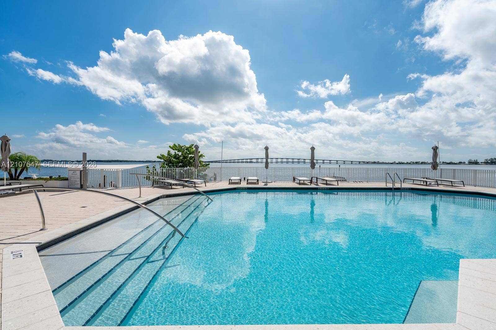 200 SE 15th Road, #PH-A, Miami, Miami, FL 33129 Swimming pool featuring a sun shelf entry, stainless steel handrails, tiled decking, and perimeter fencing