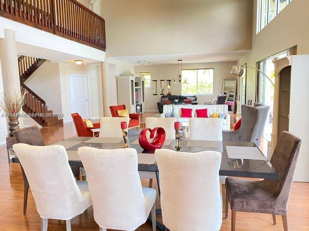Double-height ceilings, open-concept floor plan, hardwood flooring, wood-railed staircase, and expansive windows