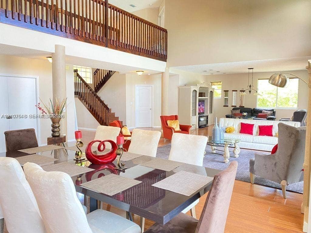Two-story interior featuring wood-finish flooring, an open mezzanine with a wood railing, a sweeping staircase, and recessed lighting