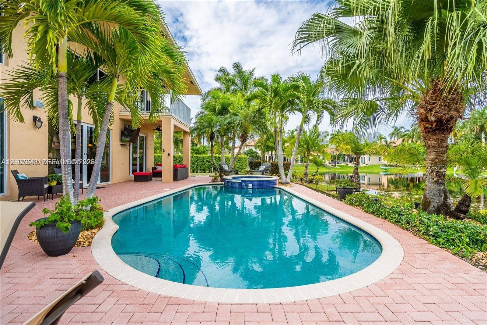 Swimming pool with built-in spa, brick paver decking, two-story covered patio, and established palm trees