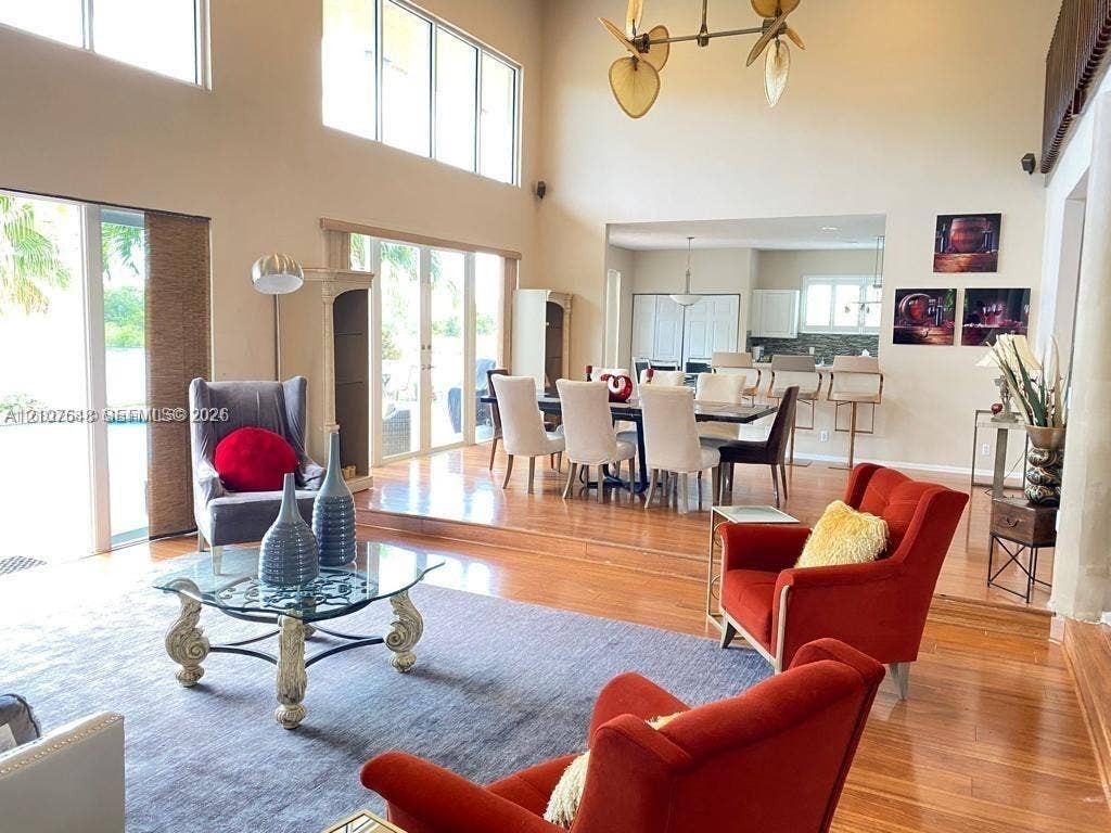 Double-height ceilings with floor-to-ceiling windows, wood-finish flooring, multi-level layout, and large glass-paned double doors