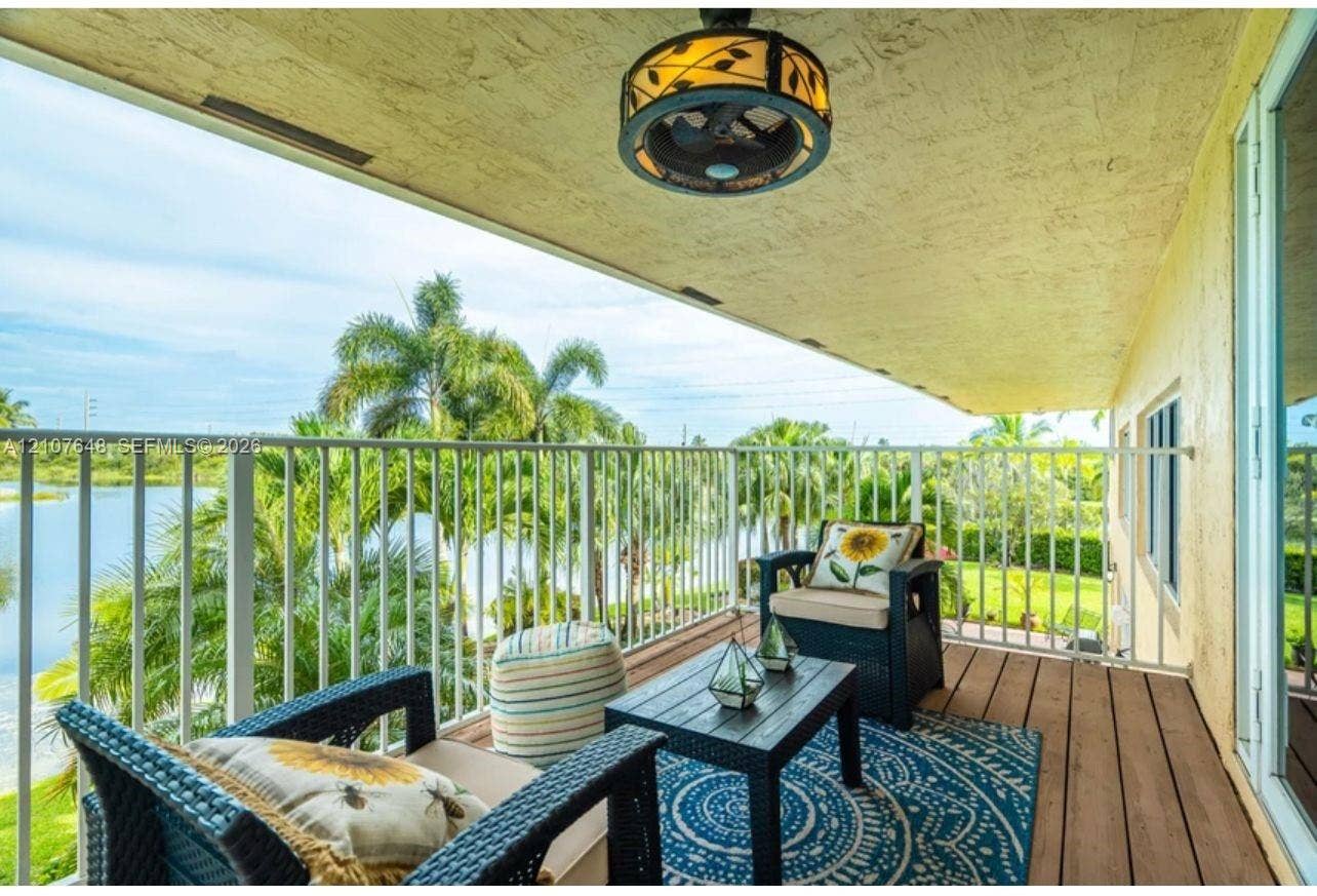 Covered balcony featuring wood-finish flooring, white metal railing, and a decorative ceiling-mounted light fixture