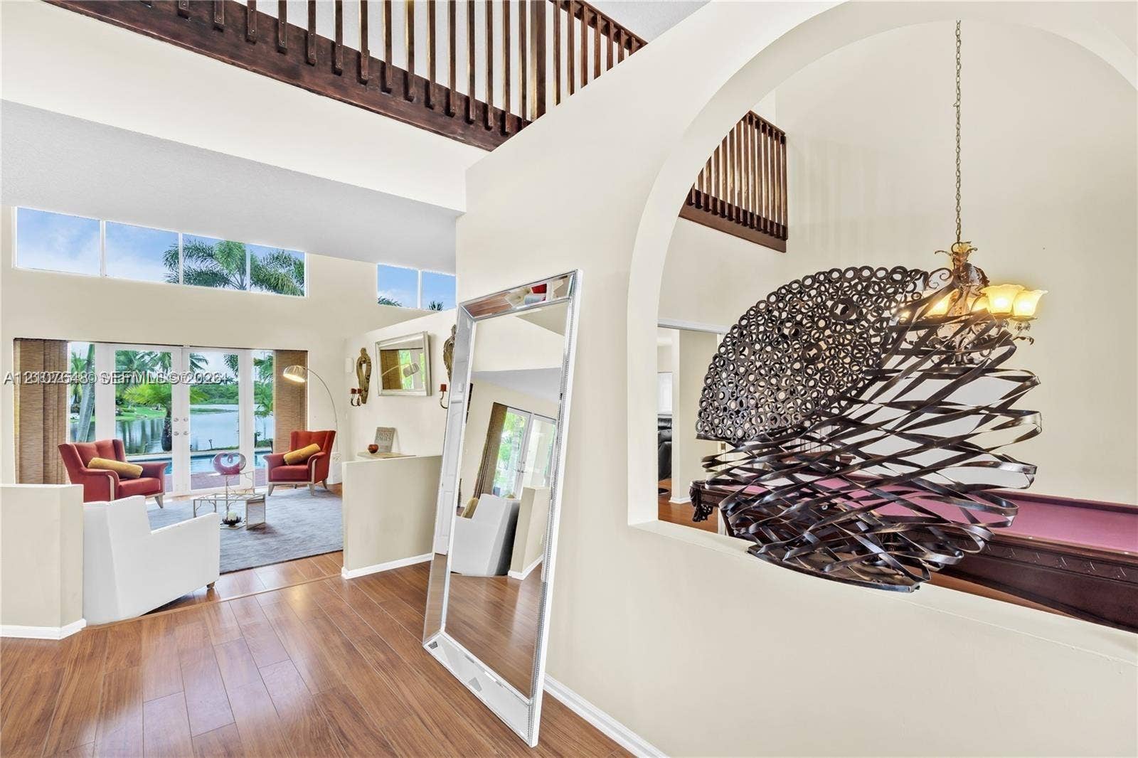 Open floor plan featuring wood-finish flooring, vaulted ceilings, decorative arched wall openings, a suspended metal chandelier, and floor-to-ceiling windows