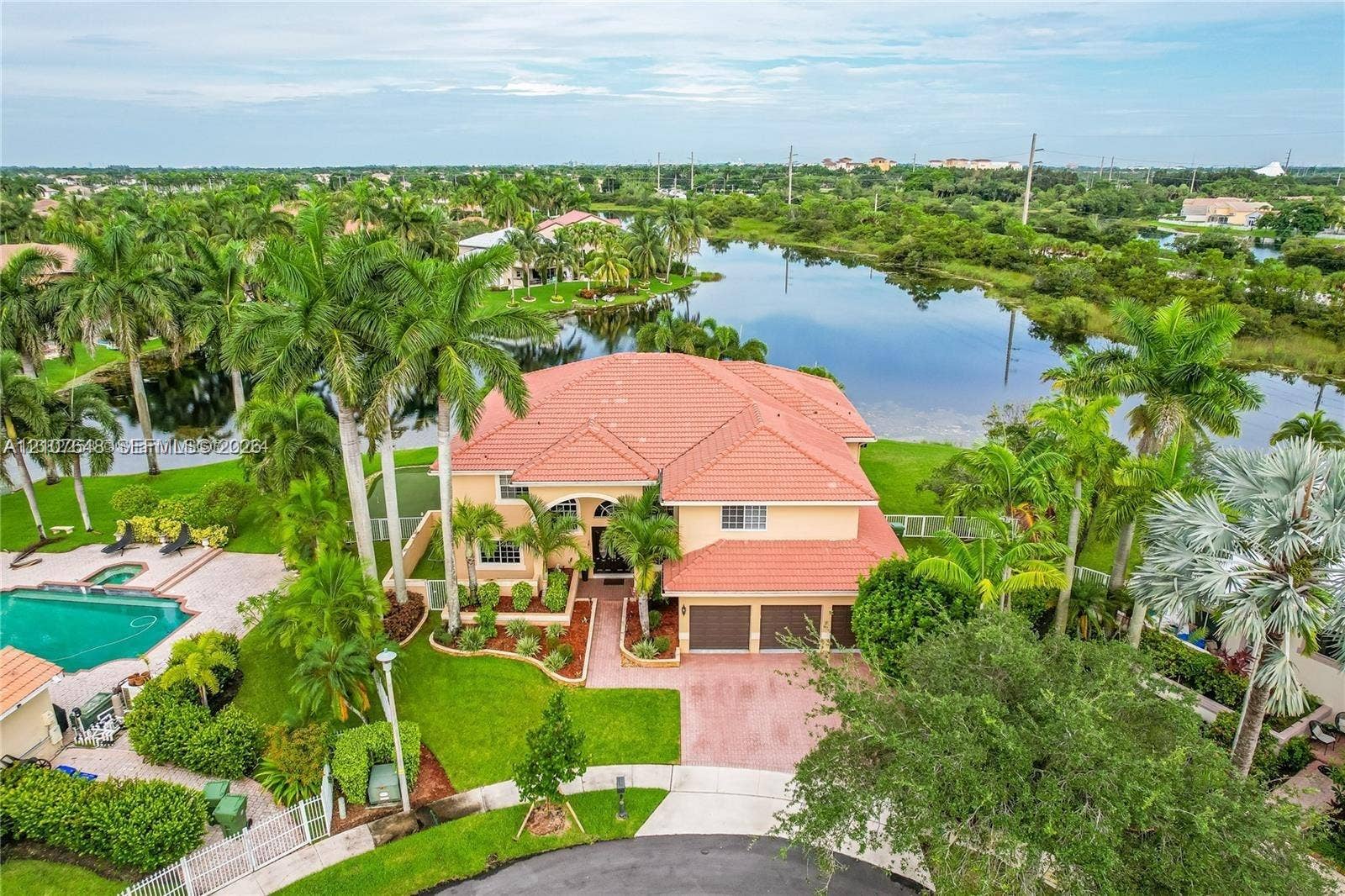 Two-story residence featuring a tile roof, three-car garage, private swimming pool, and water frontage on a landscaped lot