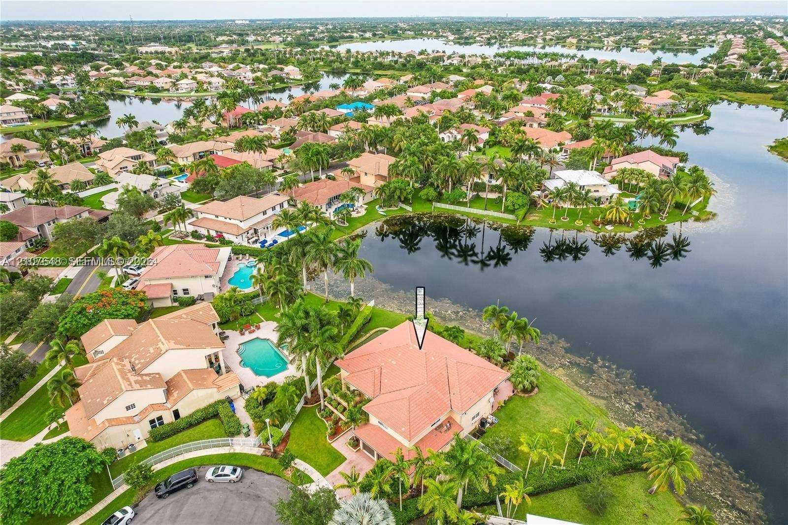 Waterfront property featuring a red tile roof, multi-level structural design, and manicured landscaping